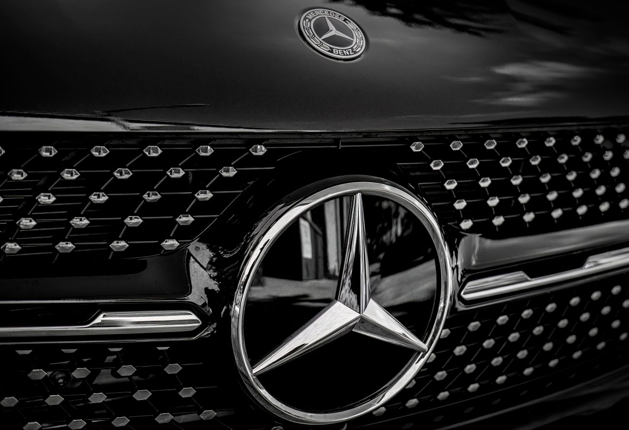 Detailed close-up of a Mercedes-Benz emblem on a luxury vehicle in black and white.