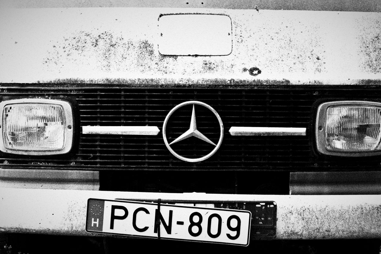 Close-up of a vintage Mercedes-Benz grille with license plate in black and white.